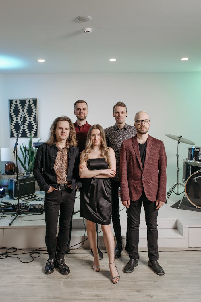 A stylish group of musicians posing confidently indoors with musical instruments.
